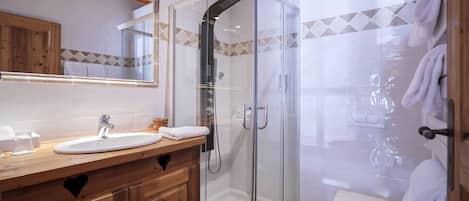 A modern bathroom with a glass-enclosed shower, a wooden vanity with a sink, and a toilet.