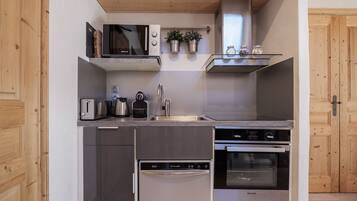 A compact kitchen with a toaster, kettle, sink, and Brandt appliances.