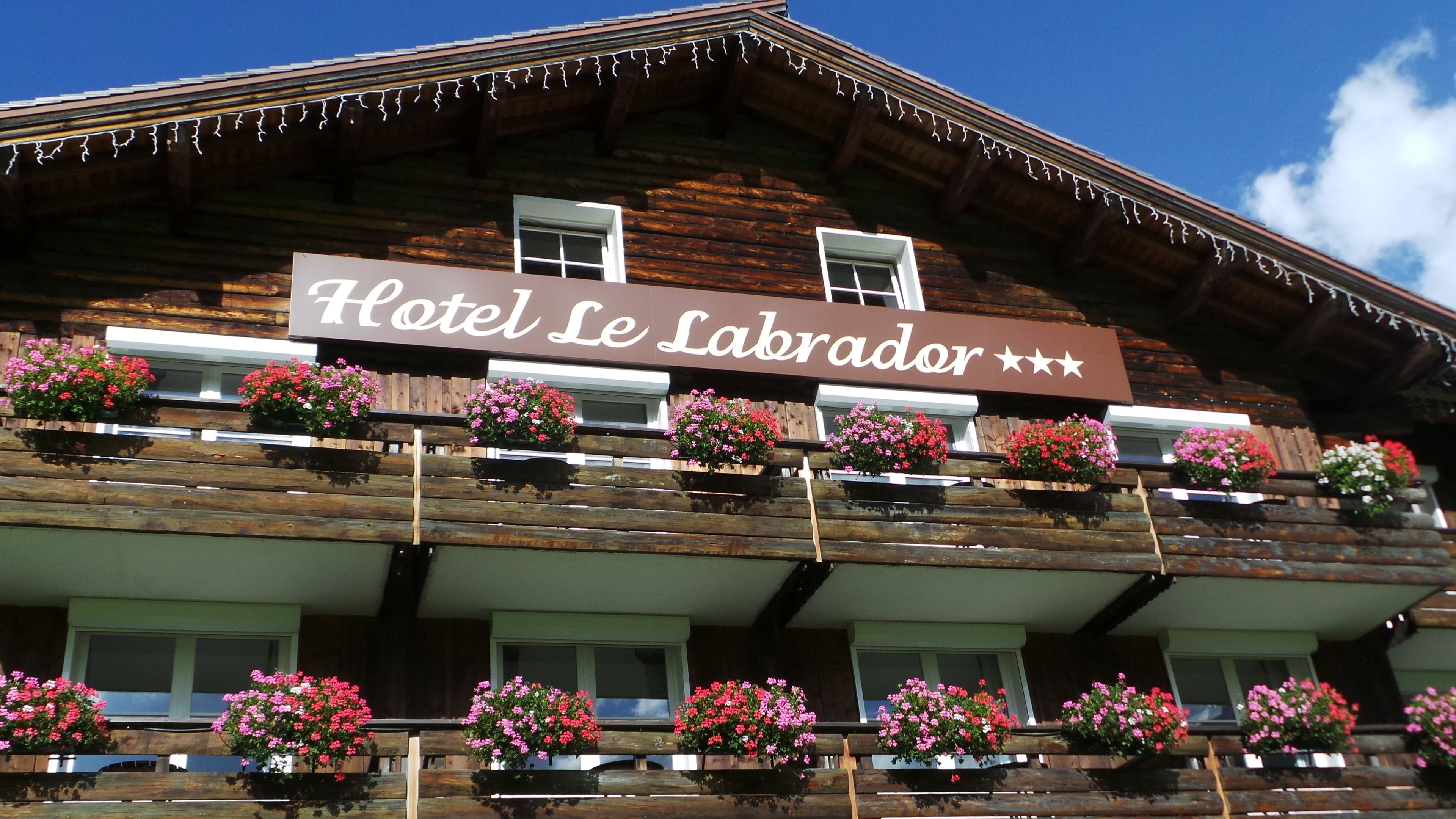 Un bâtiment en bois sur lequel est apposée une enseigne indiquant « Hôtel Le Labrador ».