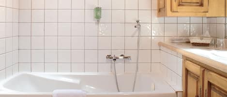 Un baño con bañera, tragaluz, paredes de azulejos y armarios de madera.