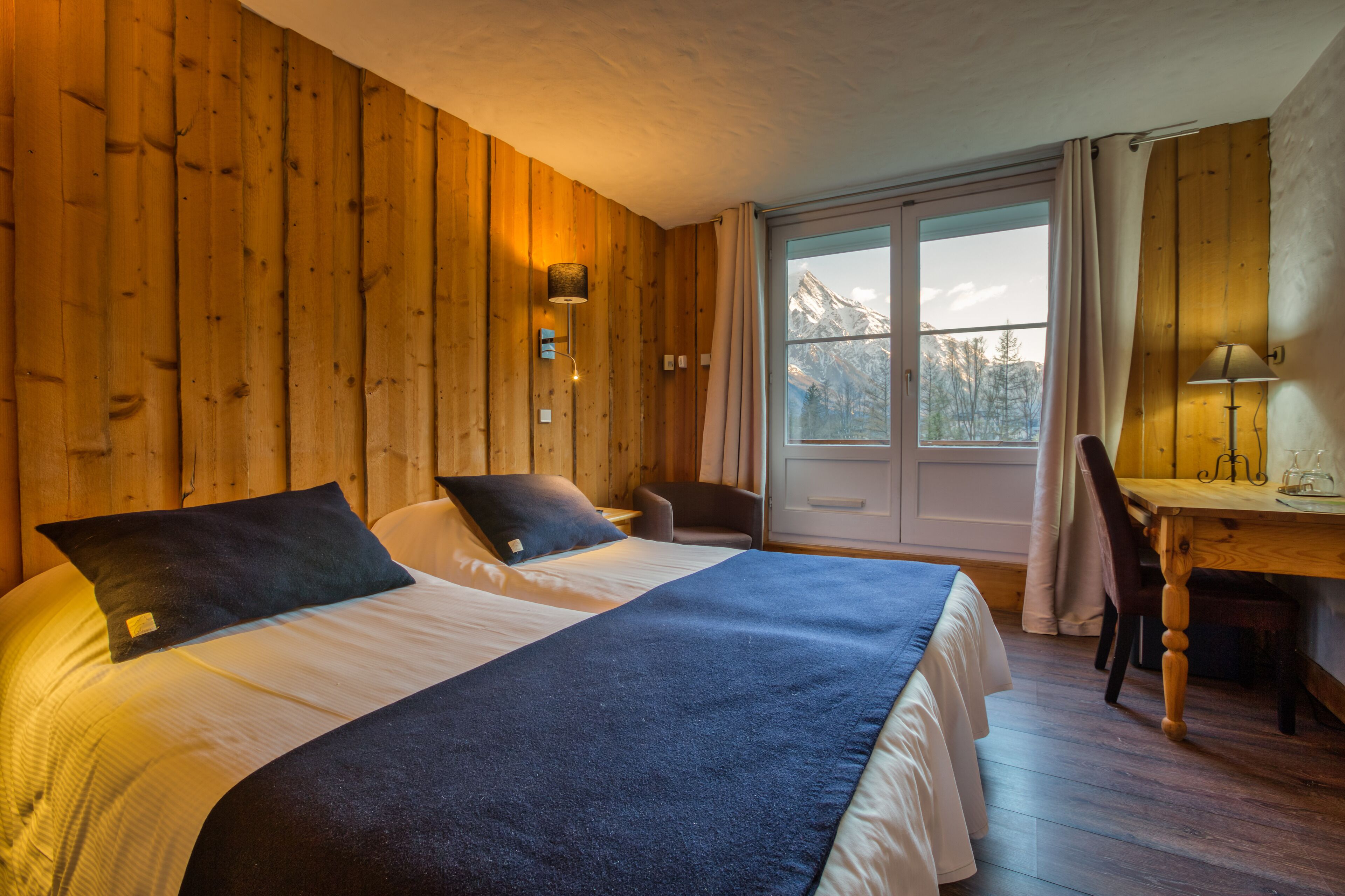 Ein Zimmer mit Holzboden, einem Bett, einem Schreibtisch und einem Stuhl.