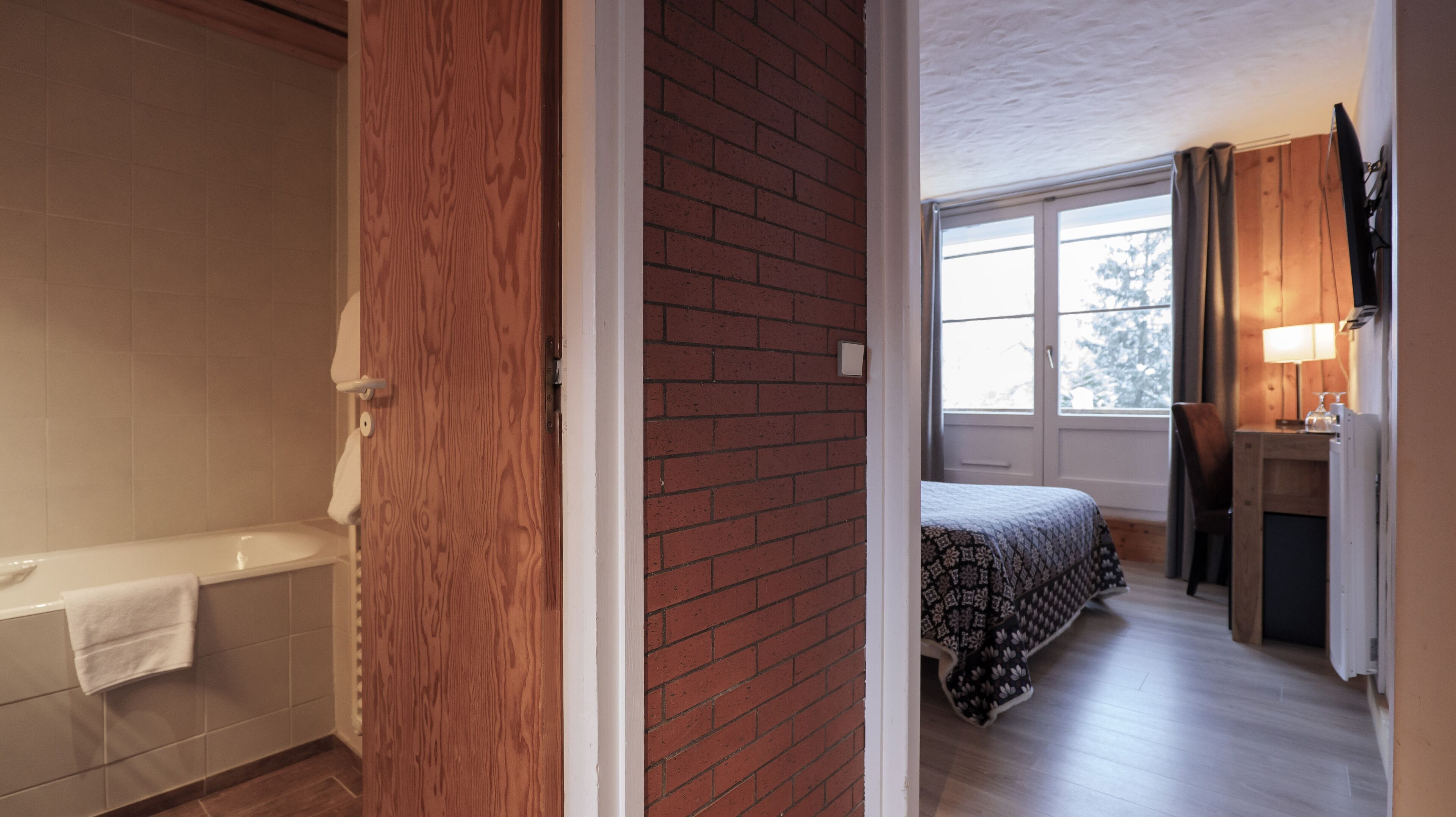 Een badkamer met een bad, een houten deur en een raam.
