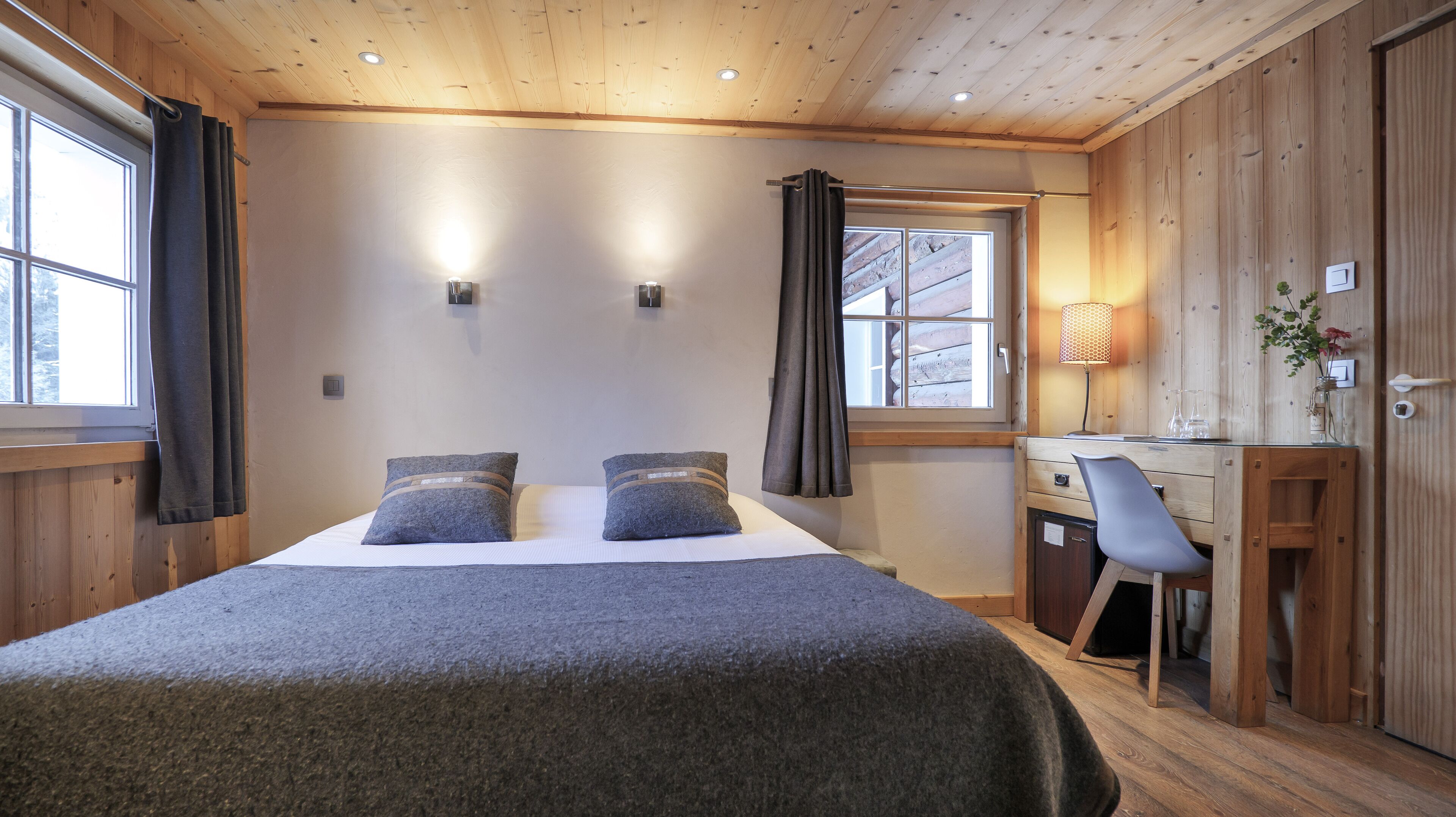 Un dormitorio acogedor con cama, dos almohadas, un escritorio y una silla.