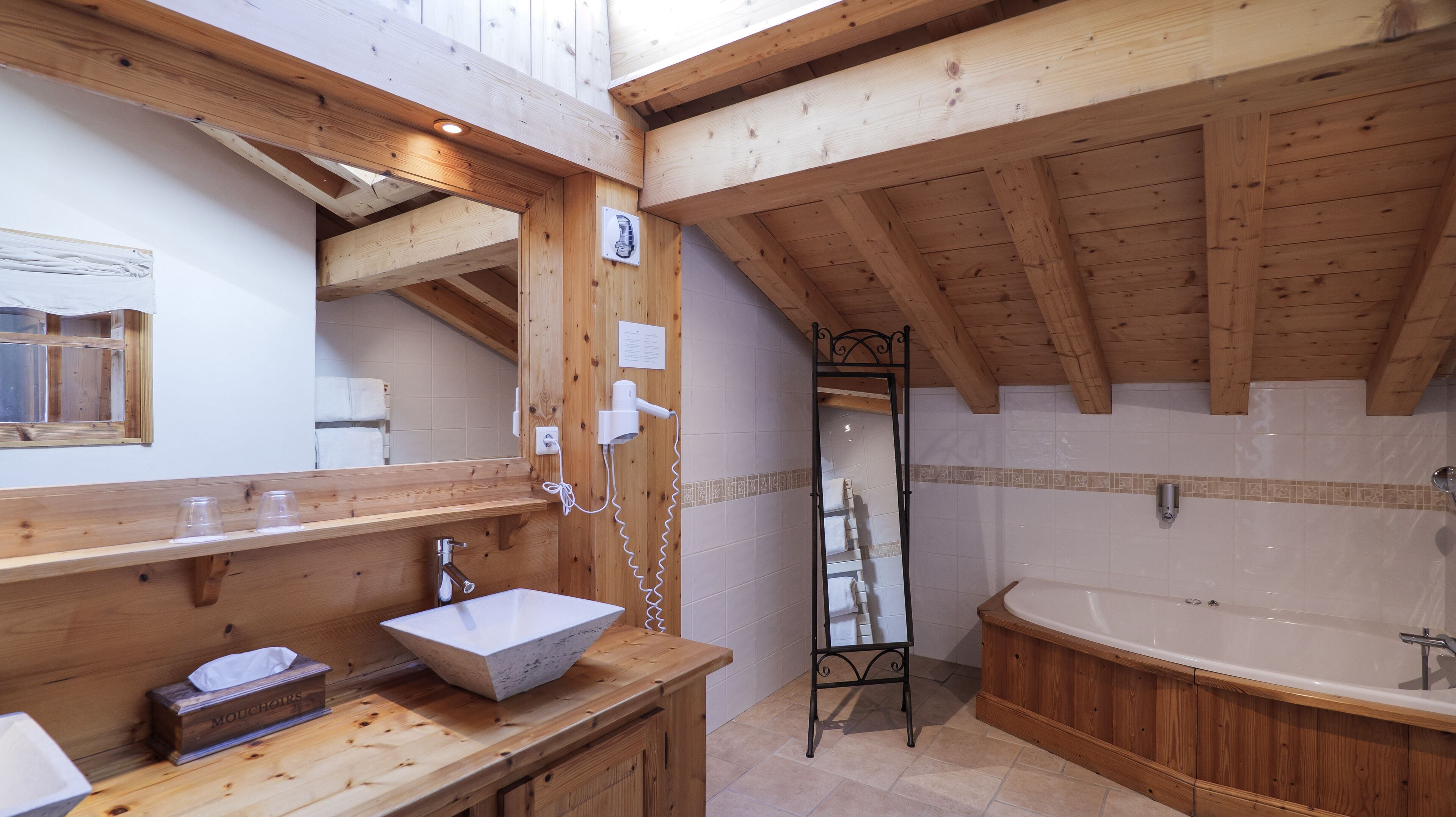 Un baño de madera con un lavamanos grande, un espejo y una bañera.