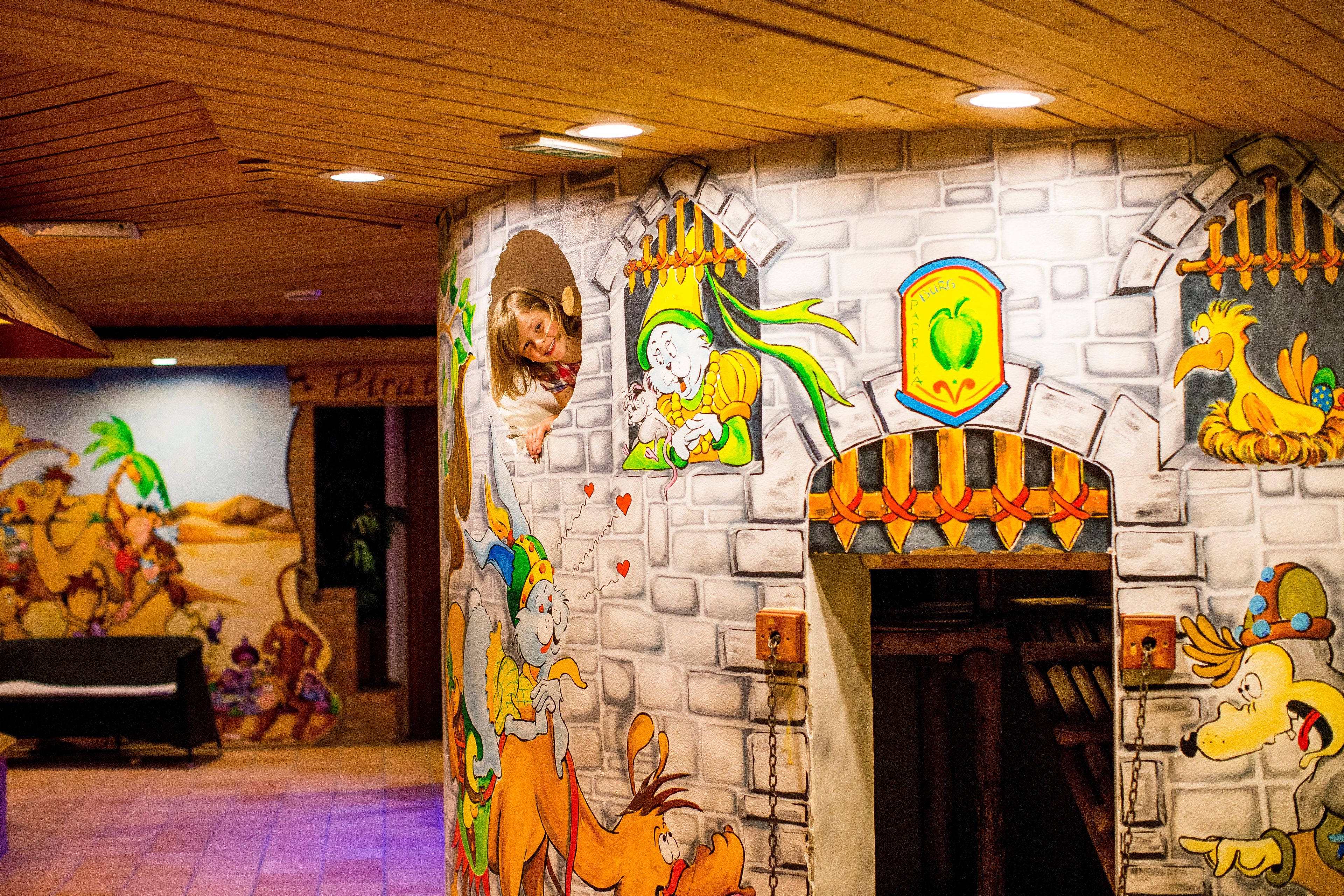 A room with a brick wall mural, a wooden ceiling, and a door leading to another room.