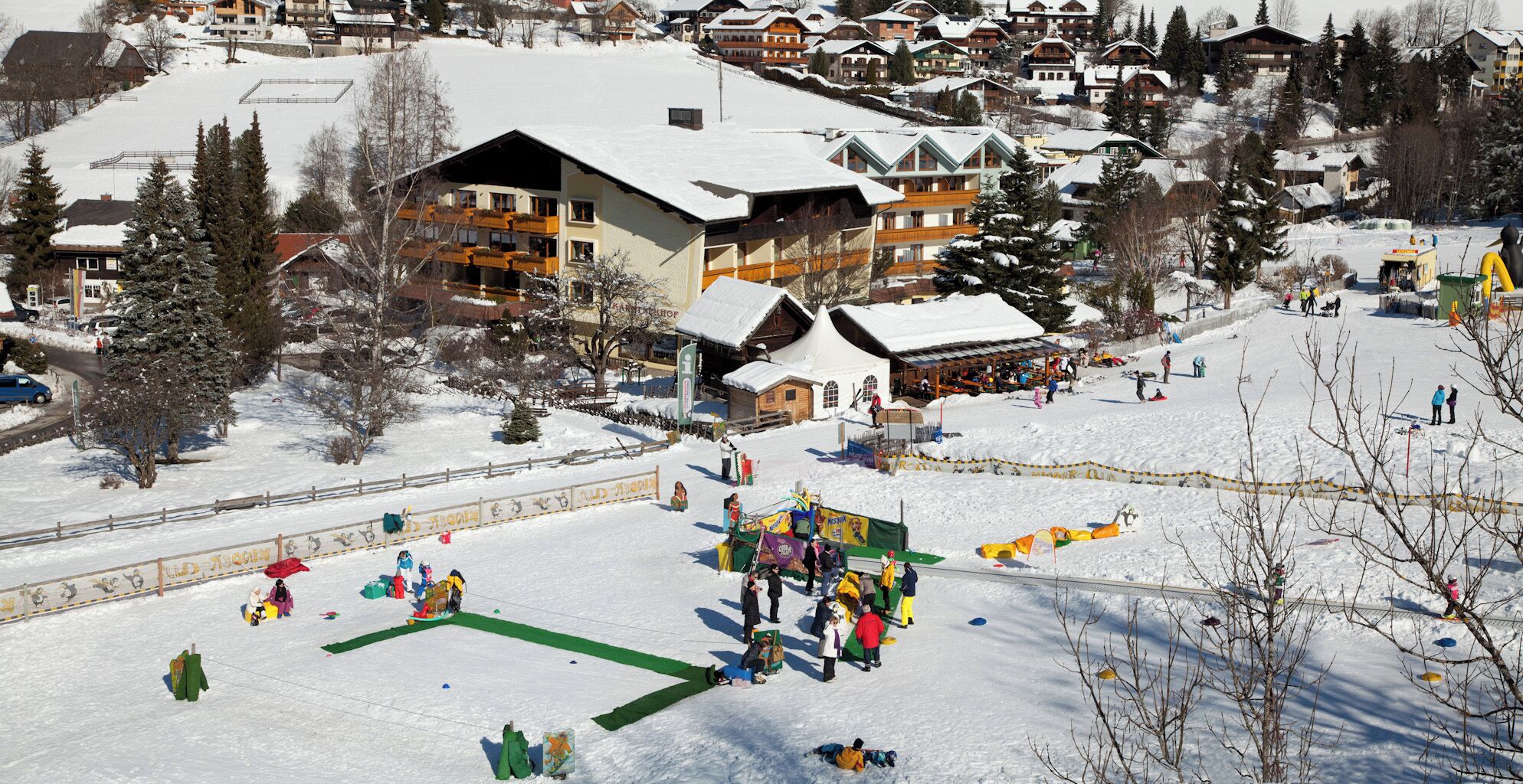 Ein Skigebiet mit einem großen Chalet, Skipisten und einem Snowpark mit verschiedenen Aktivitäten.
