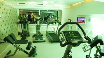 Un gimnasio con cintas de correr, elípticas y máquinas de pesas.