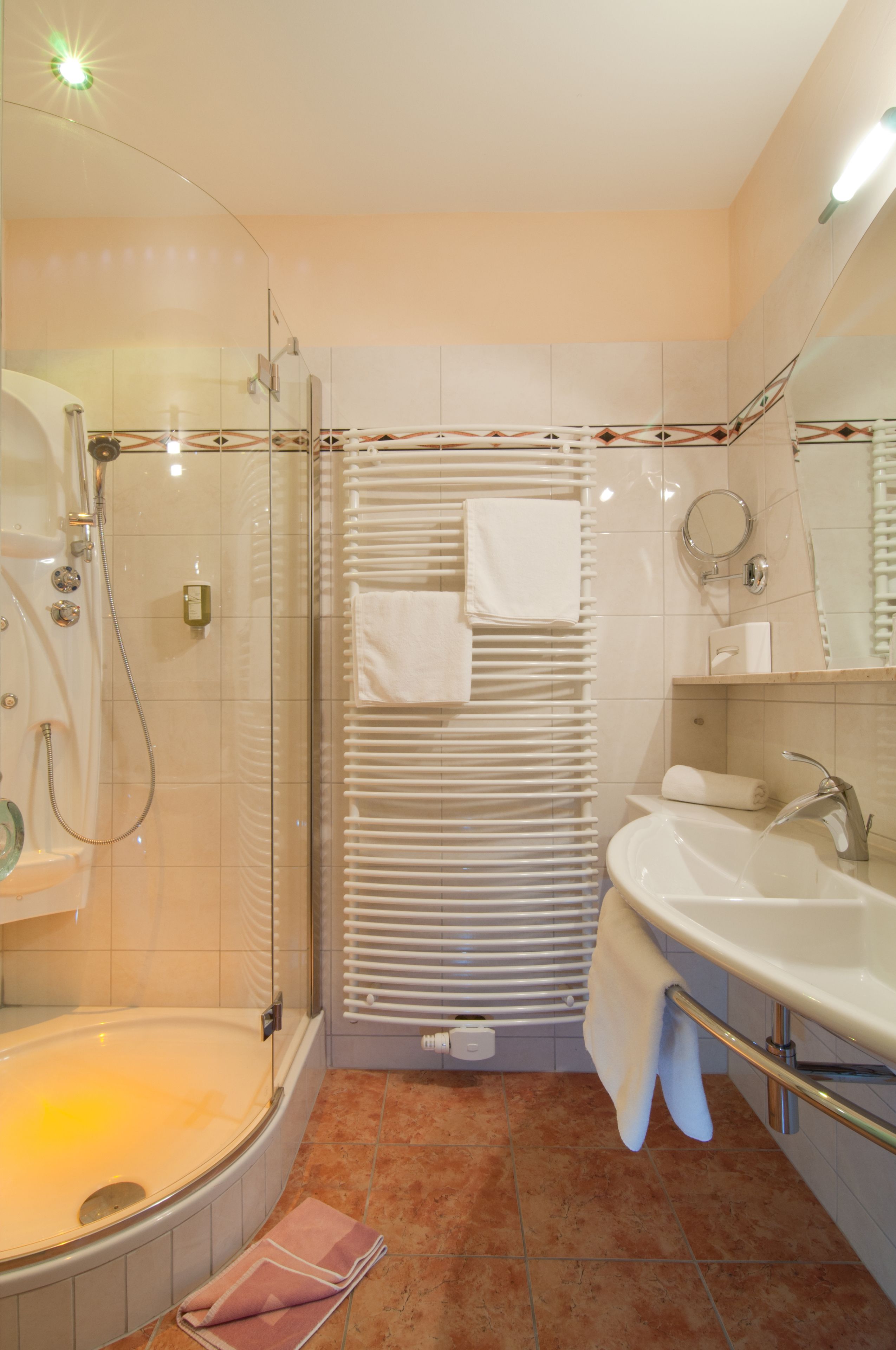 Un baño moderno con ducha de vidrio, bañera, lavamanos y toallero.