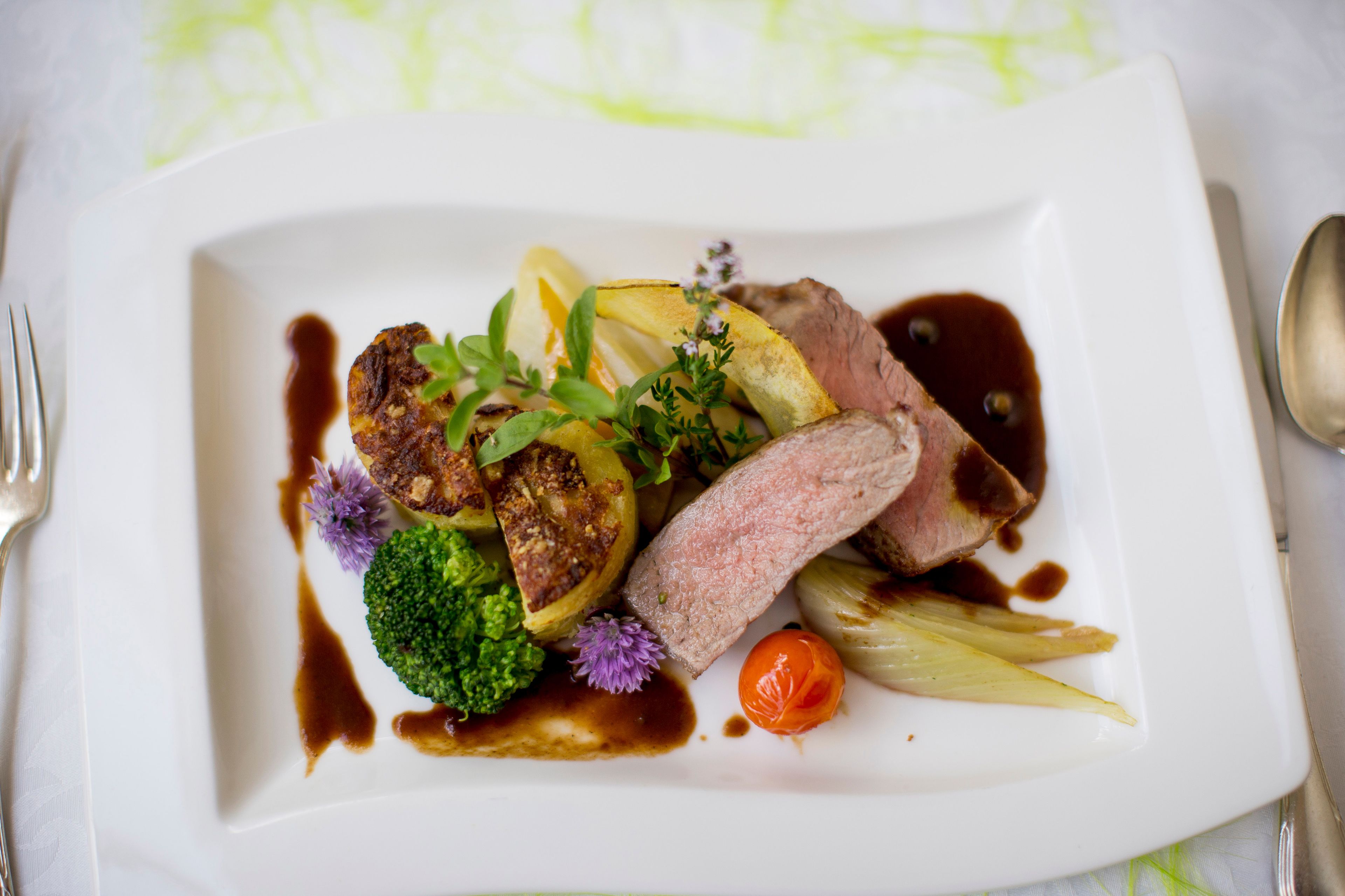 A white plate with a steak, roasted potatoes, and vegetables.