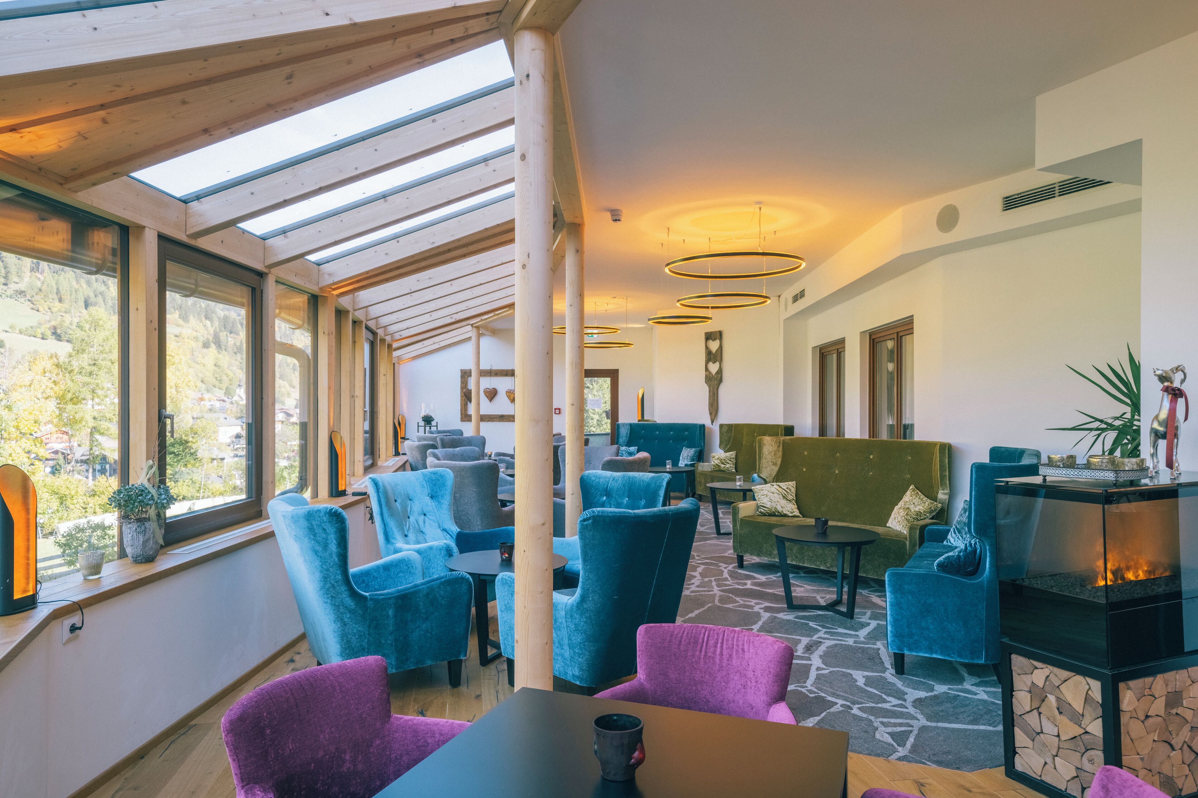 A modern interior with a high ceiling, skylights, and a stone floor. There are multiple seating areas with sofas and chairs.
