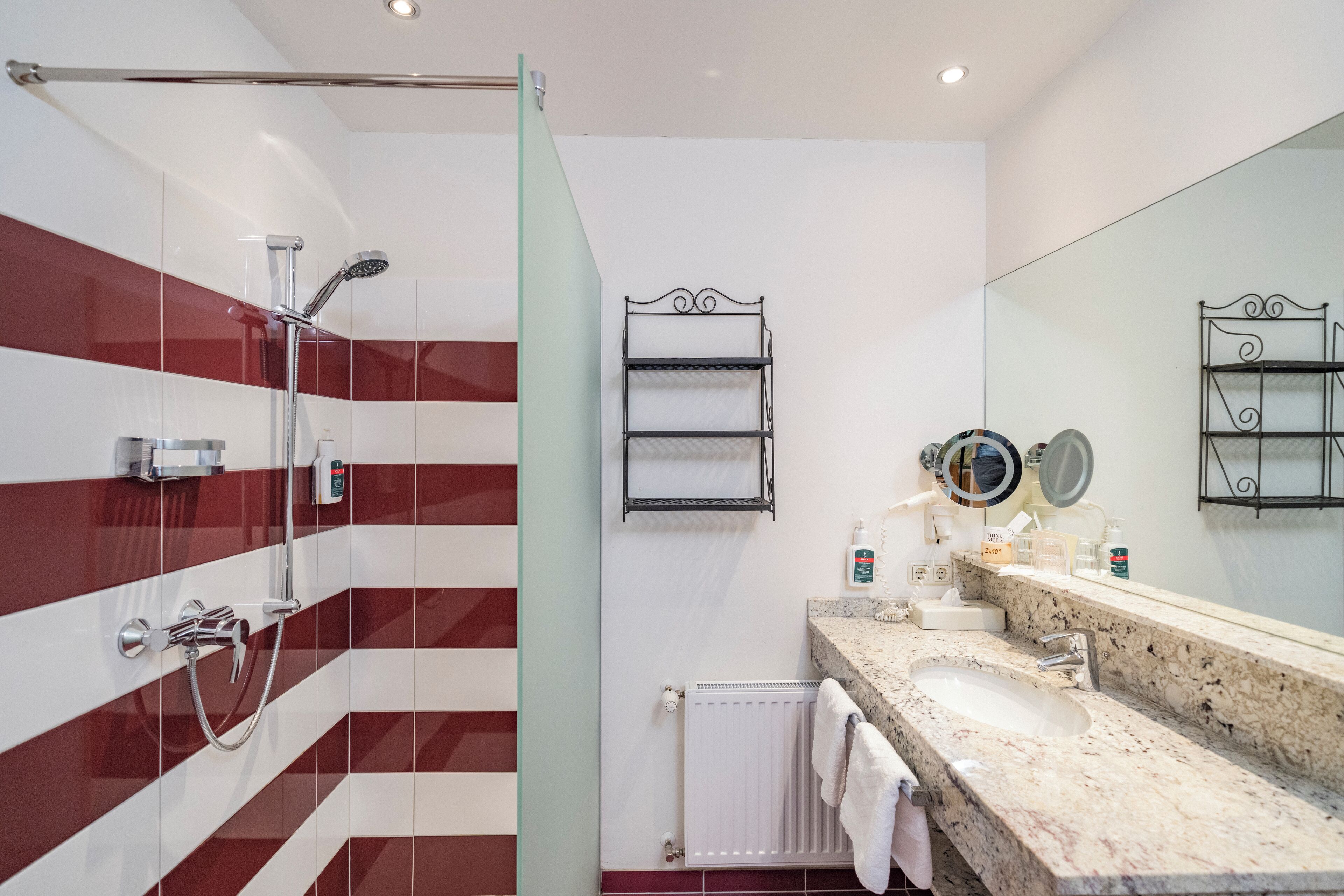 Un bagno moderno con box doccia in vetro, un mobile lavabo con piano in granito e uno specchio grande.