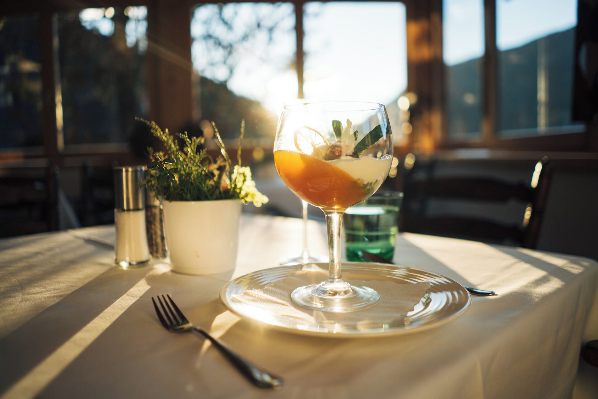 Ein Tisch mit einem Cocktailglas, einer Gabel und einer Topfpflanze.