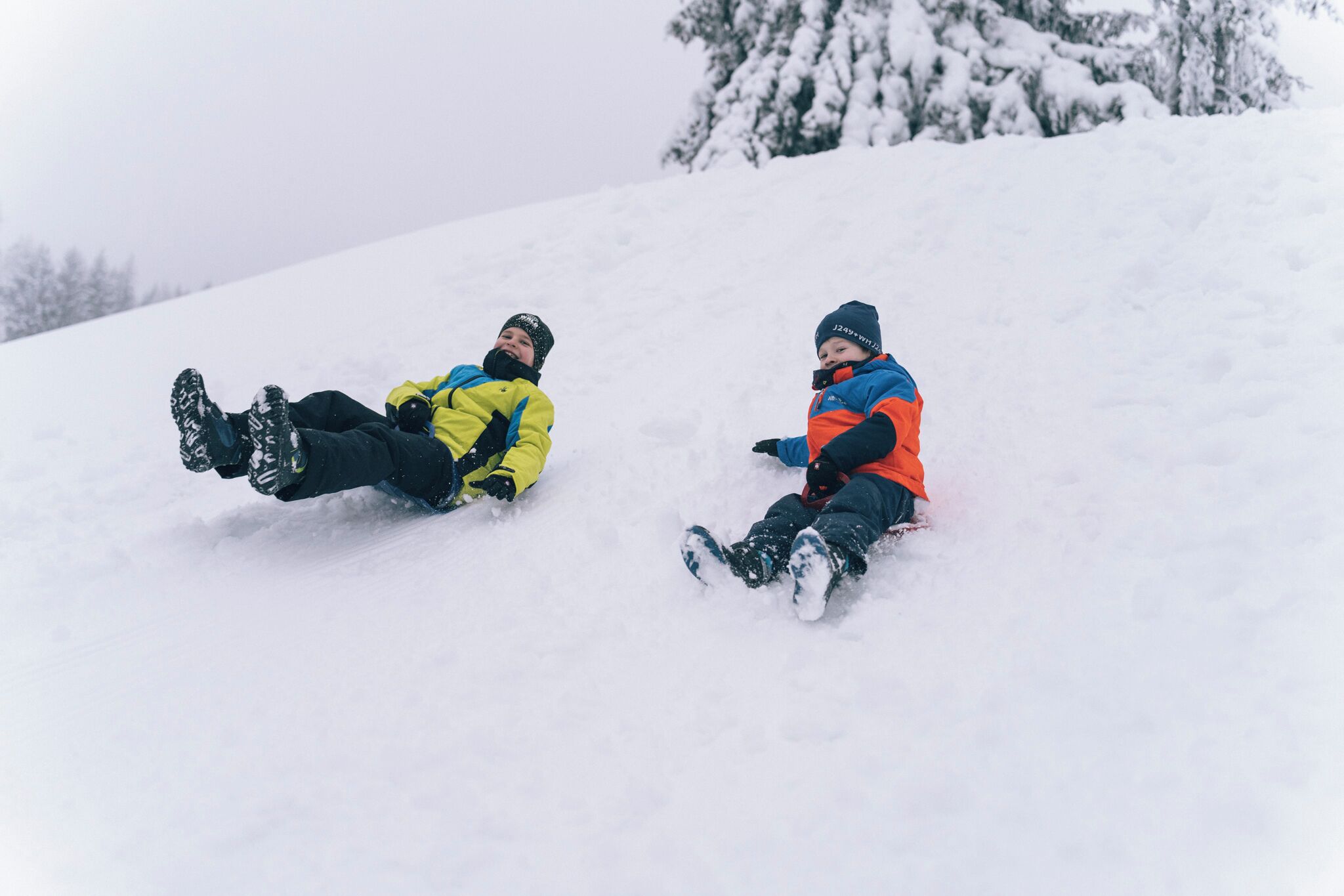 Two people sledding down a snowy slope.