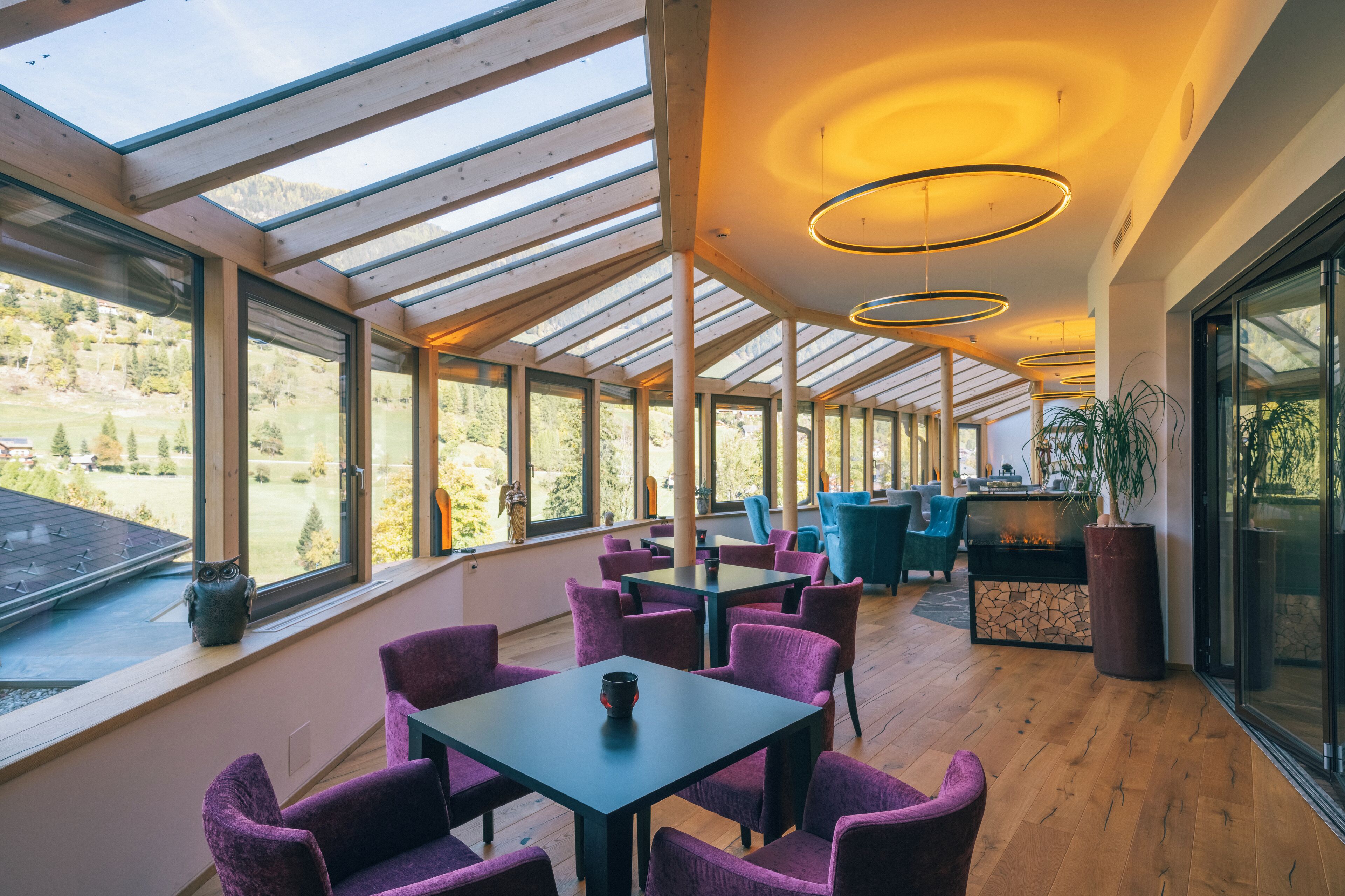 A spacious indoor area with wooden flooring, large windows, and modern lighting fixtures.