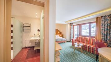 Una habitación de hotel con baño, cama, sofá y zona de comedor.