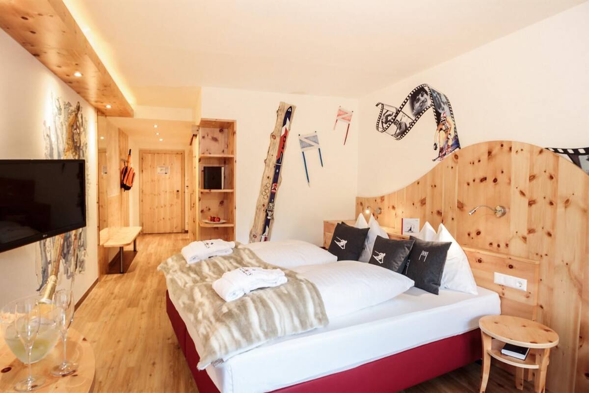 Una habitación de hotel moderna con una cama grande, cabecero de madera y televisor de pantalla plana.