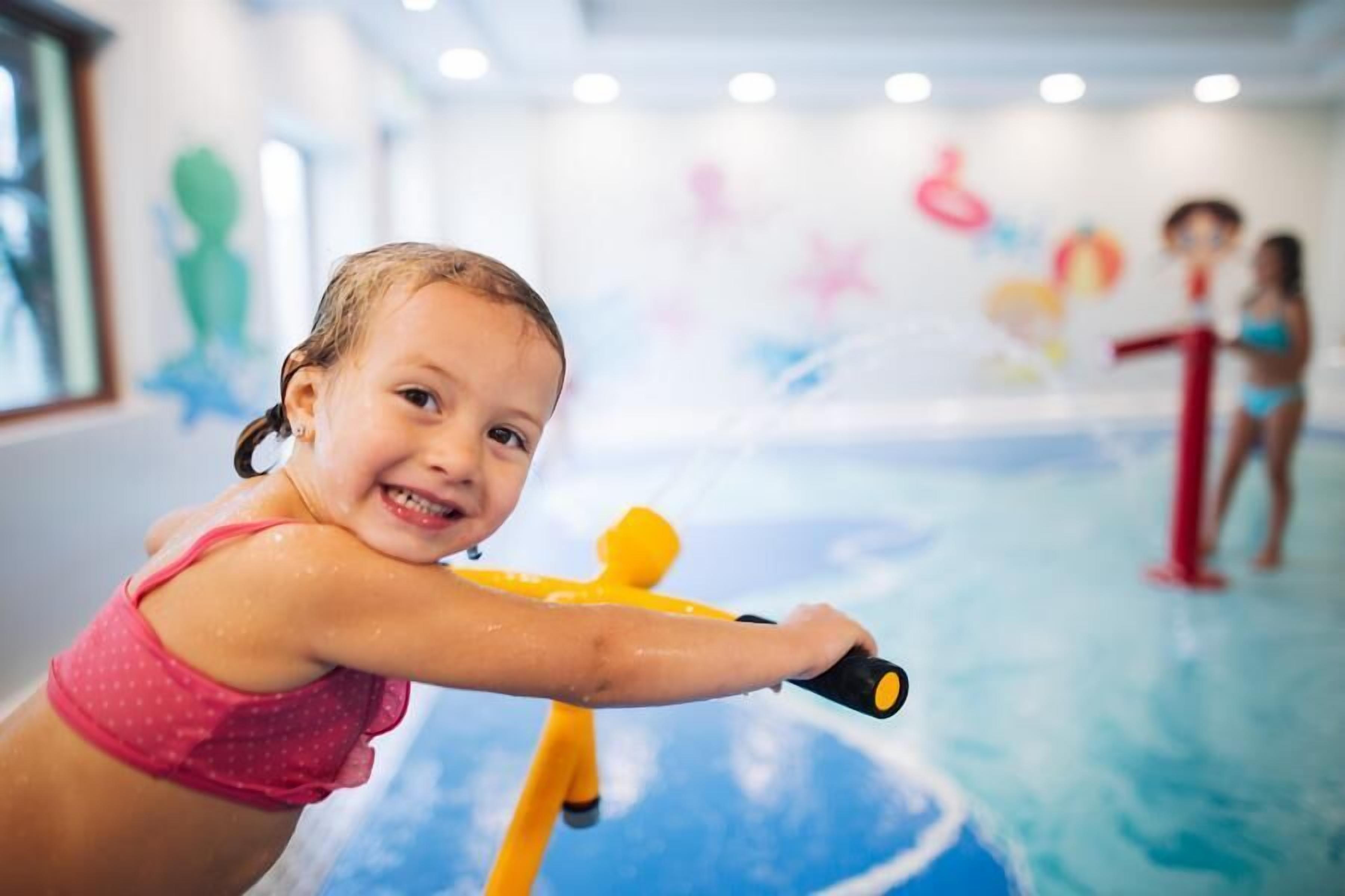 A child playing with a water toy in a room with a blue floor and colorful wall decorations.