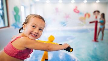 A child playing with a water toy in a room with a blue floor and colorful wall decorations.