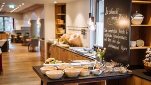 A buffet setup with various food items and a chalkboard sign in a restaurant. - Nationalpark Lodge Grossglockner (Heiligenblut)