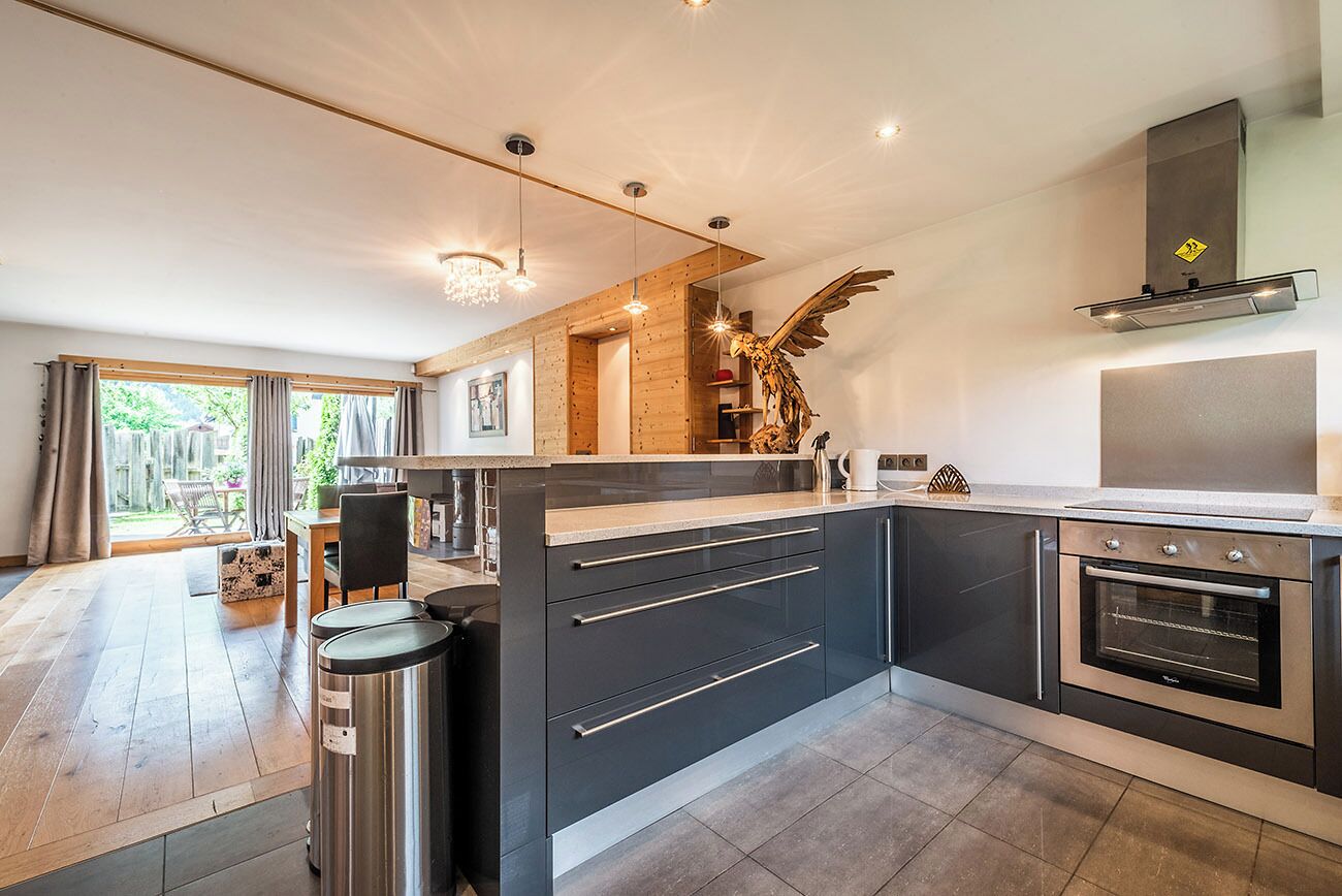 A modern kitchen with dark cabinetry, stainless steel appliances, and a large island.