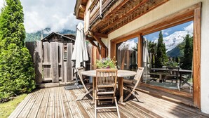 A wooden deck with a round table and chairs, a wooden fence, and a mountain view. - Hotel Eden Chamonix (Chamonix-Mont-Blanc)