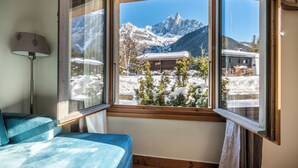 A room with a large window offering a view of snow-covered mountains and a wooden cabin. - Hotel Eden Chamonix (Chamonix-Mont-Blanc)