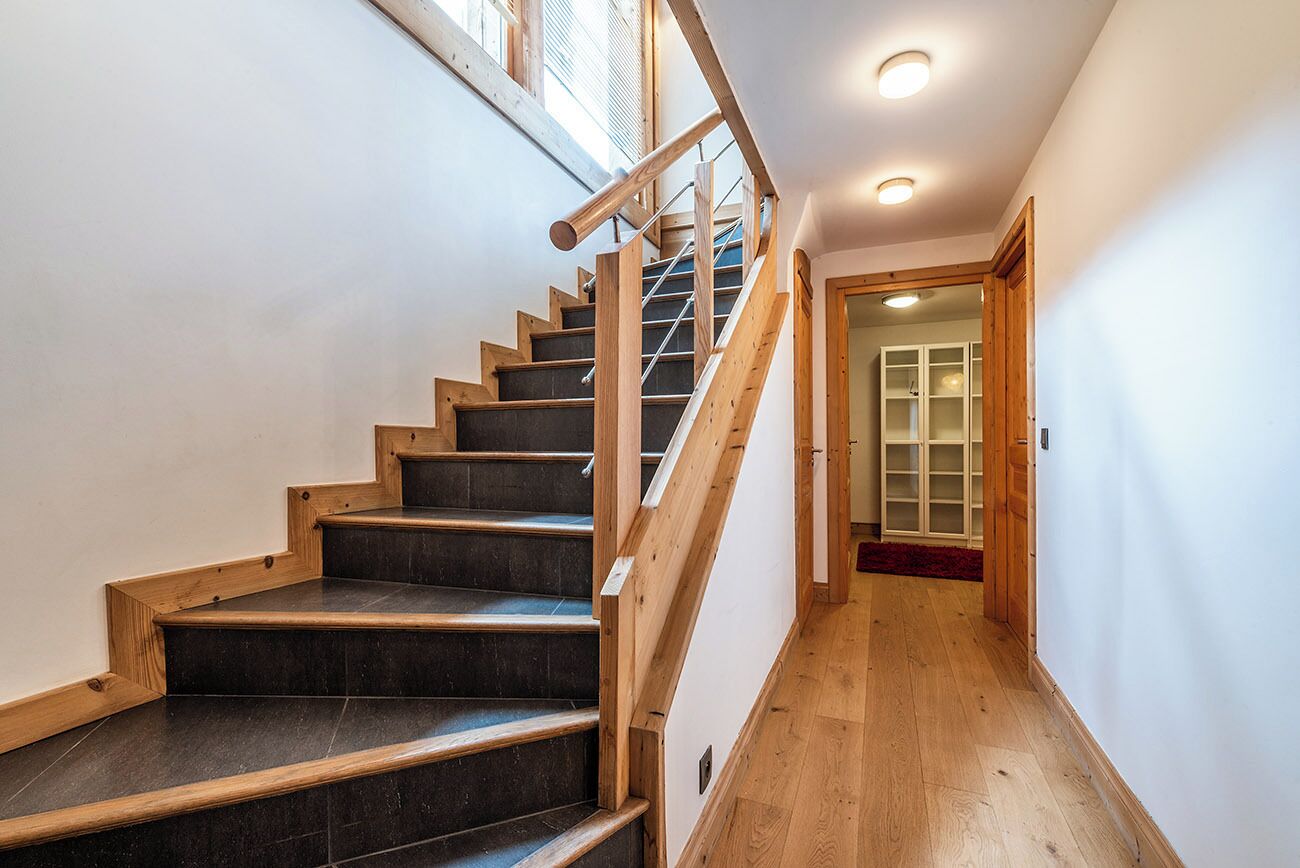 Eine Treppe mit Holzboden und Metallgeländer, die zu einem Raum mit Holztür und rotem Teppich führt.