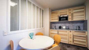 A modern kitchen with wooden cabinets, a stainless steel oven, and a white dining table with chairs.