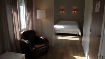 Une chambre d’hôtel avec un lit, une chaise, une lampe et une porte.