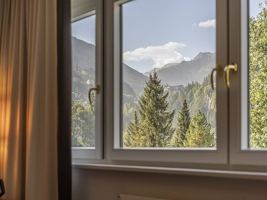 Una ventana con vistas a un paisaje montañoso, una lámpara y un radiador.