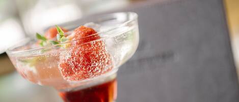 A cocktail glass with a strawberry garnish and ice cubes.