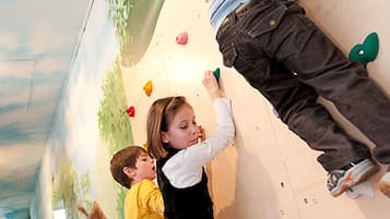 Experience the thrill of rock climbing in our indoor climbing wall, featuring a unique forest mural and varied climbing holds.