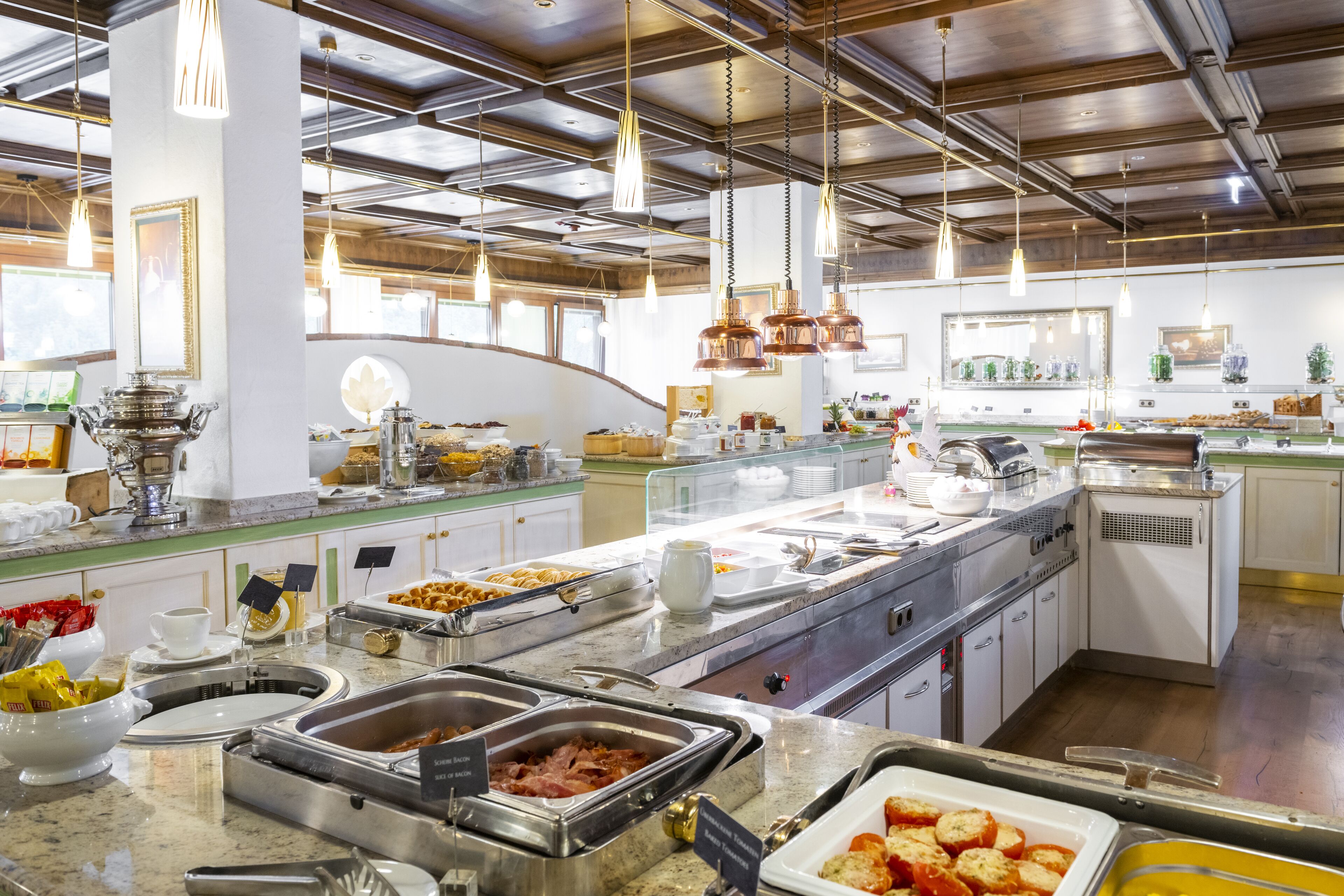 Un bufé con diferentes estaciones de comida, que incluye una barra de ensaladas, una estación de platos calientes y una estación de postres.