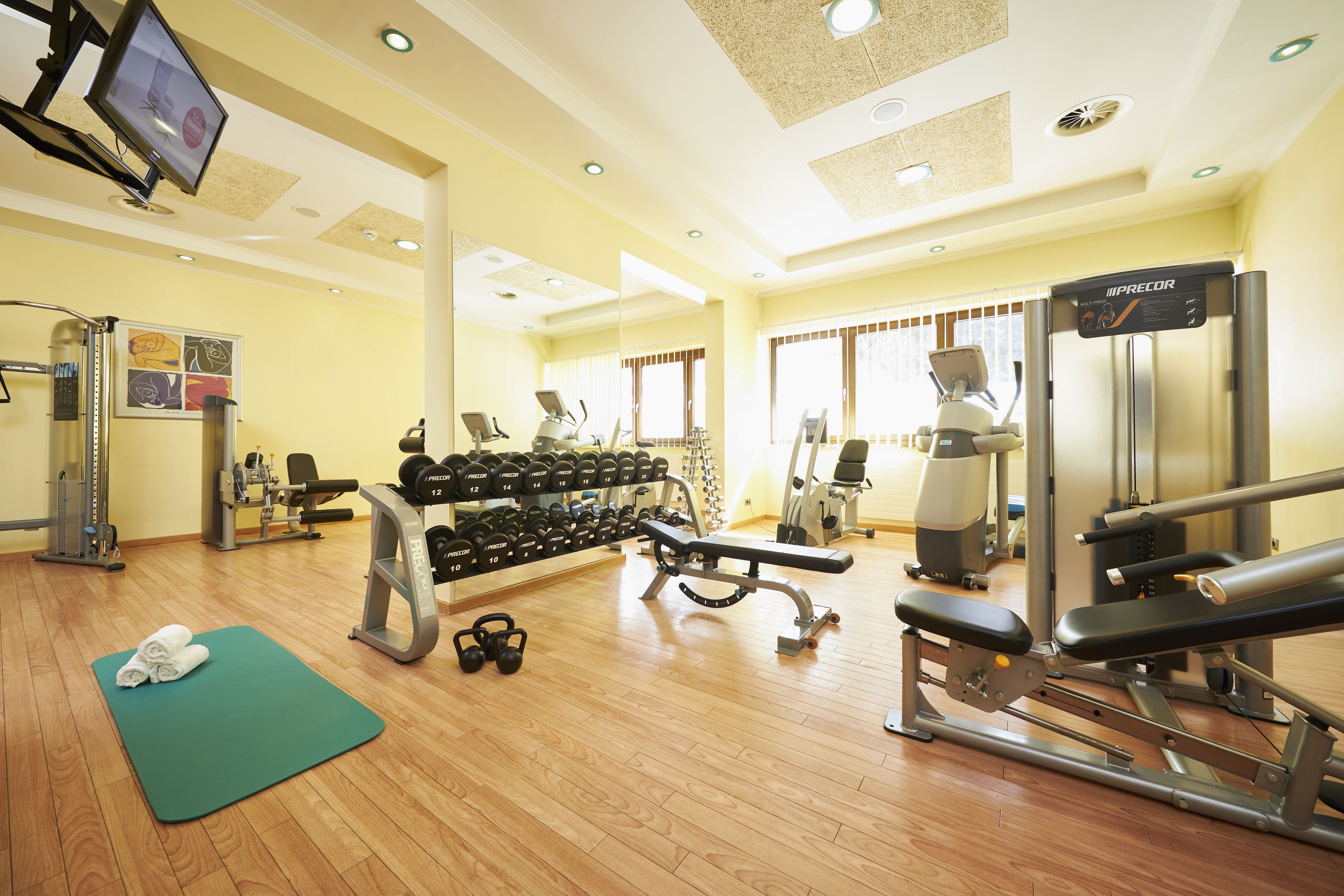 Une salle de sport équipée de matériel d’exercice, d’un téléviseur et d’un miroir.