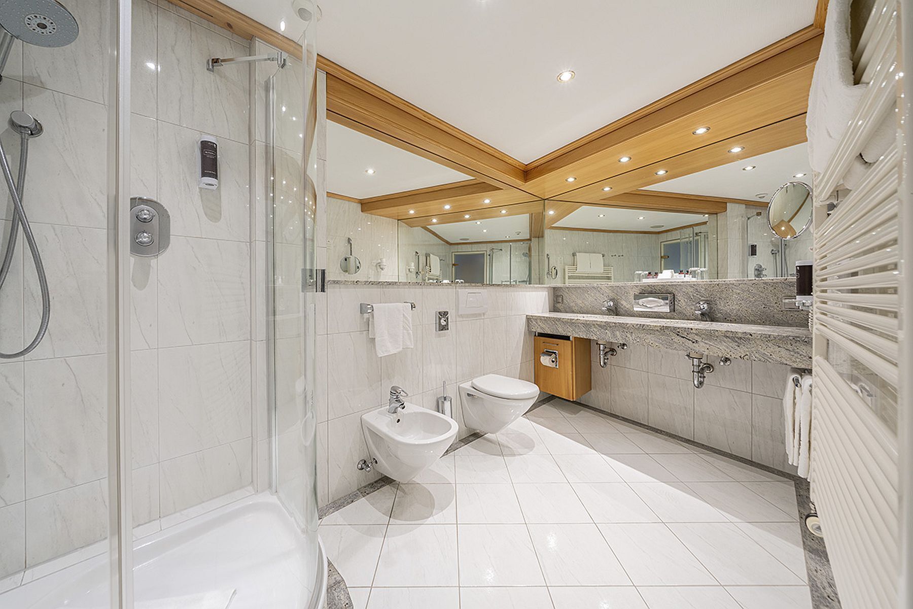 A modern bathroom with a glass-enclosed shower, a freestanding bathtub, a toilet, and a vanity with a mirror.