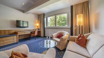 Ett hotellrum med en soffa, fåtölj, skrivbord och TV.