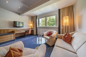 Ett hotellrum med en soffa, fåtölj, skrivbord och TV.