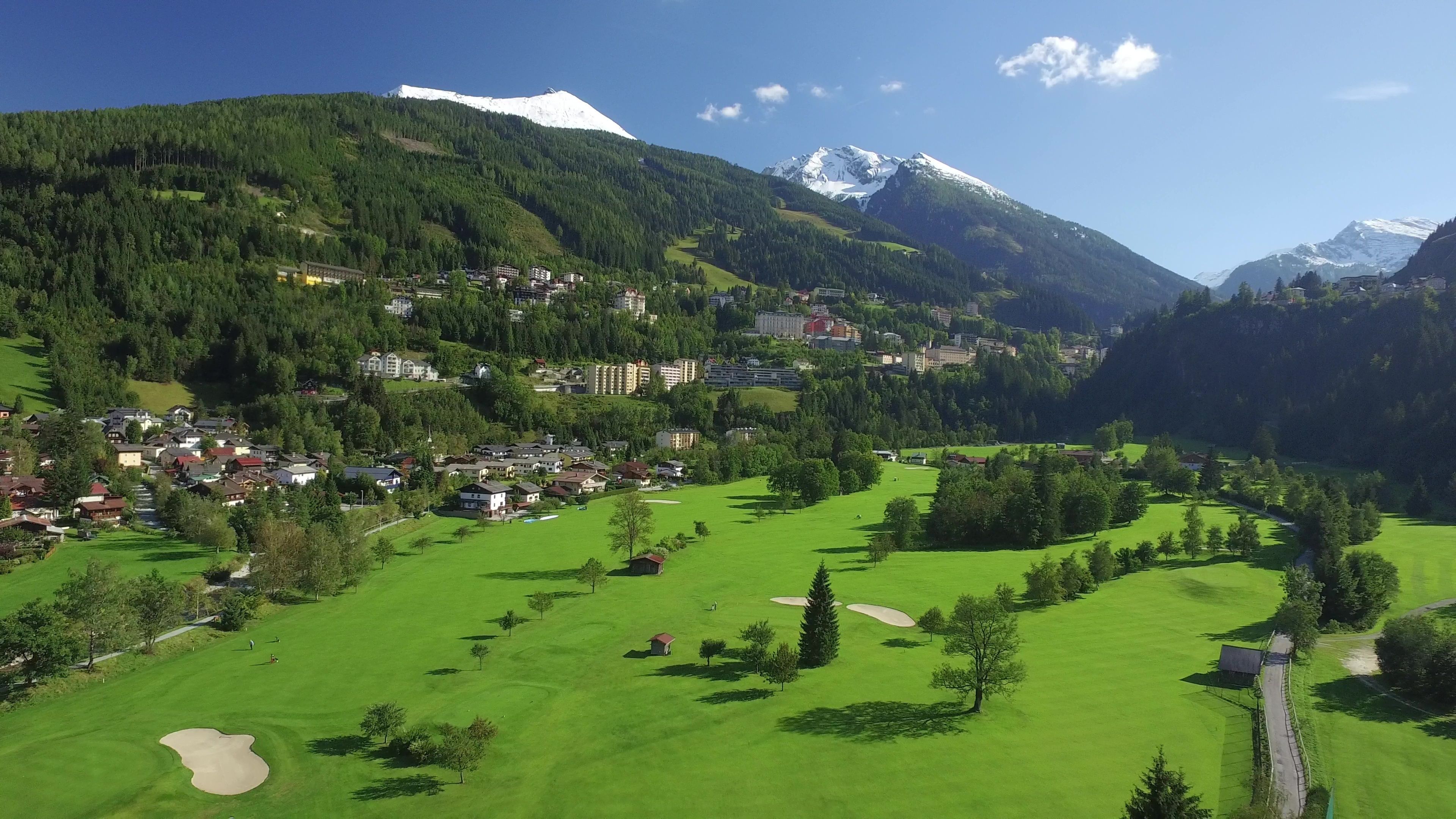 A mountainous landscape with a village, green fields, and a golf course.