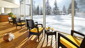 A sunlit deck with wicker furniture and a view of a snowy landscape. - EUROPÄISCHER HOF Bad Gastein (Bad Gastein)