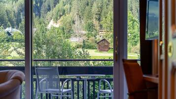 A balcony with a view of a forested area and a small wooden cabin.