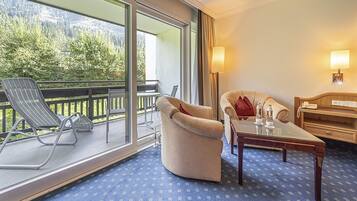 Une chambre d’hôtel avec un balcon, un canapé, une table et une lampe.