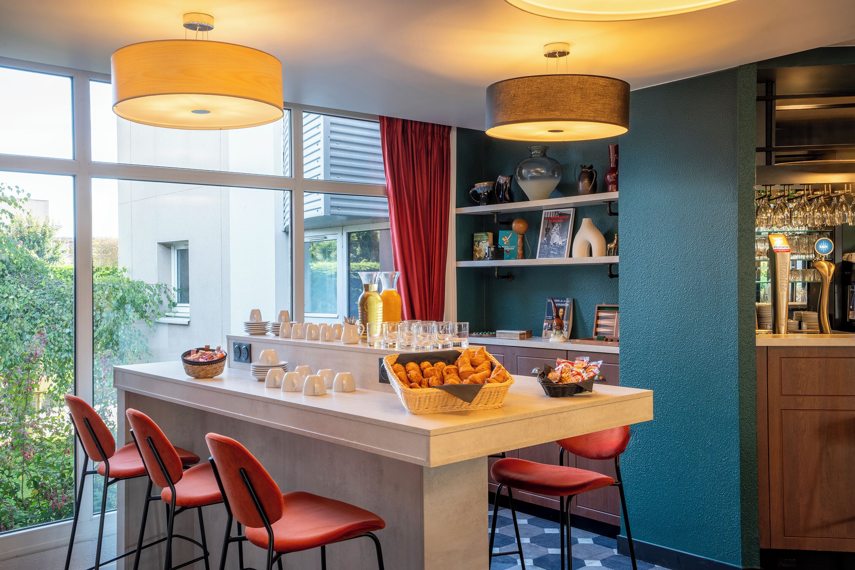 Una cocina moderna con una isla central, taburetes rojos y vistas al exterior.