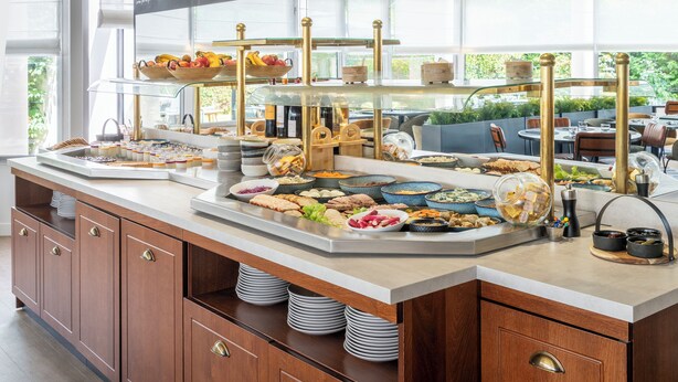 A buffet setup with various food items and a glass display case. - Le Carline, Sure Hotel Collection by Best Western (Caen)