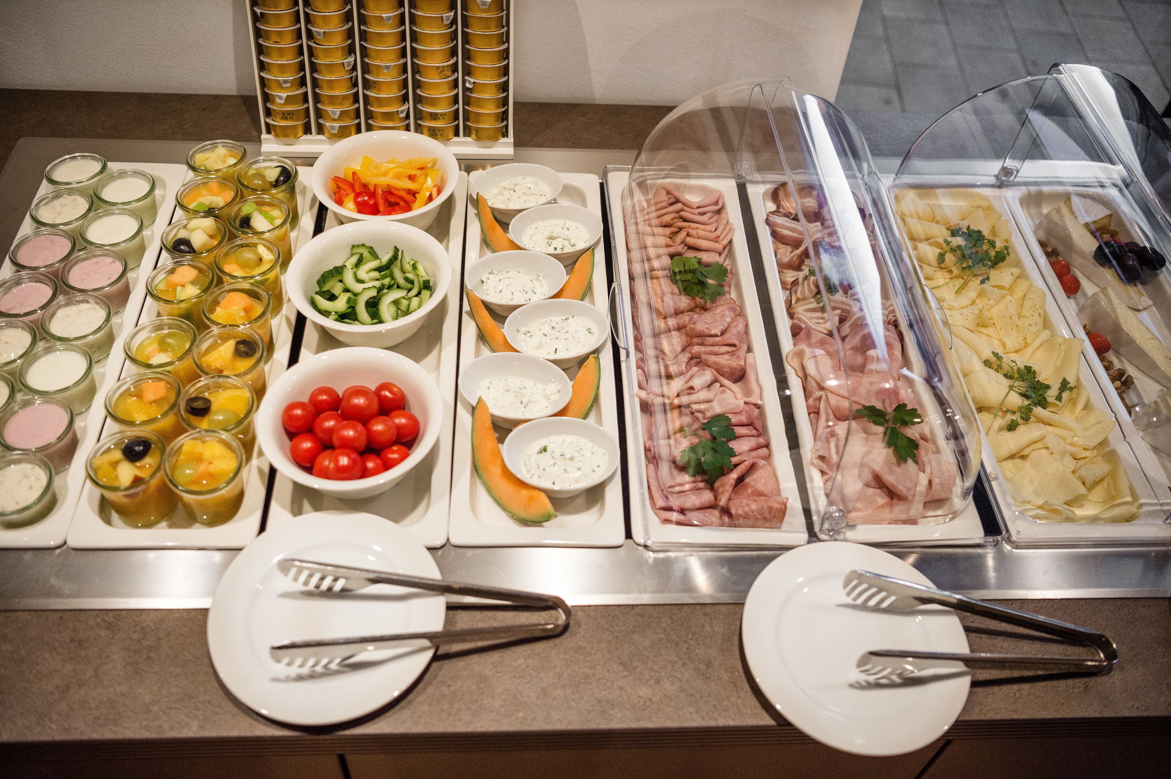 A buffet with various food items including fruits, vegetables, and meats.