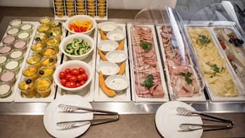 A buffet with various food items including fruits, vegetables, and meats.