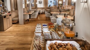 Ein Restaurant mit Holzboden, verschiedenen Sitzbereichen und einem Buffet mit vielfältigen Speisen.