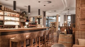 Eine moderne Bar mit einer Holztresore, Barhocker und einer Auswahl an Flaschen und Gläsern.