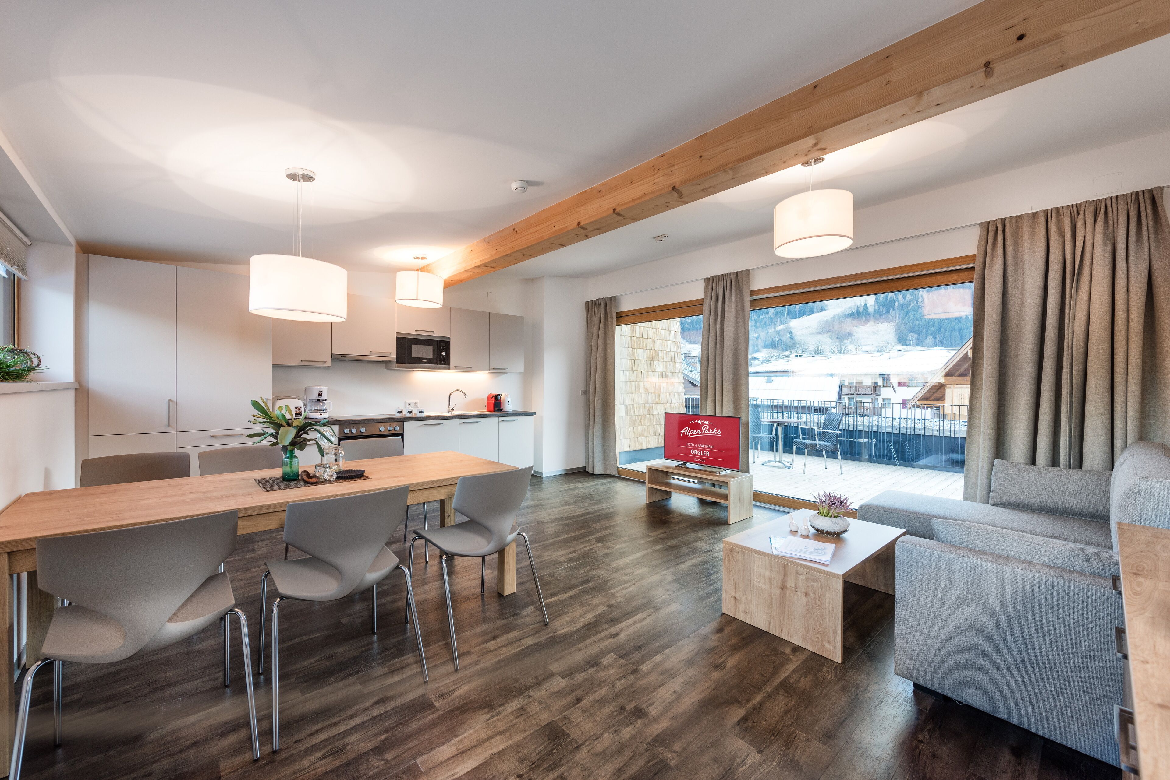 Ein modernes Wohnzimmer mit einem Holzesstisch, grauen Stühlen, einer Couch und einem Couchtisch.