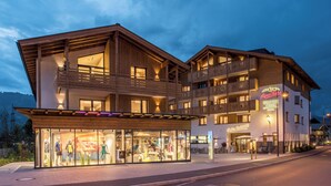 Ein Hotel mit mehreren Balkonen, einem Restaurant und einem Geschäft mit Schaufensterpuppen.