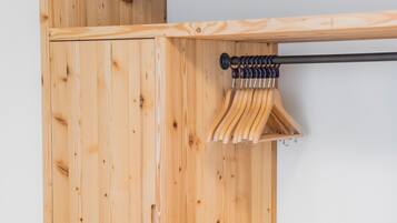 A wooden wardrobe with a hanging rod and a bench.